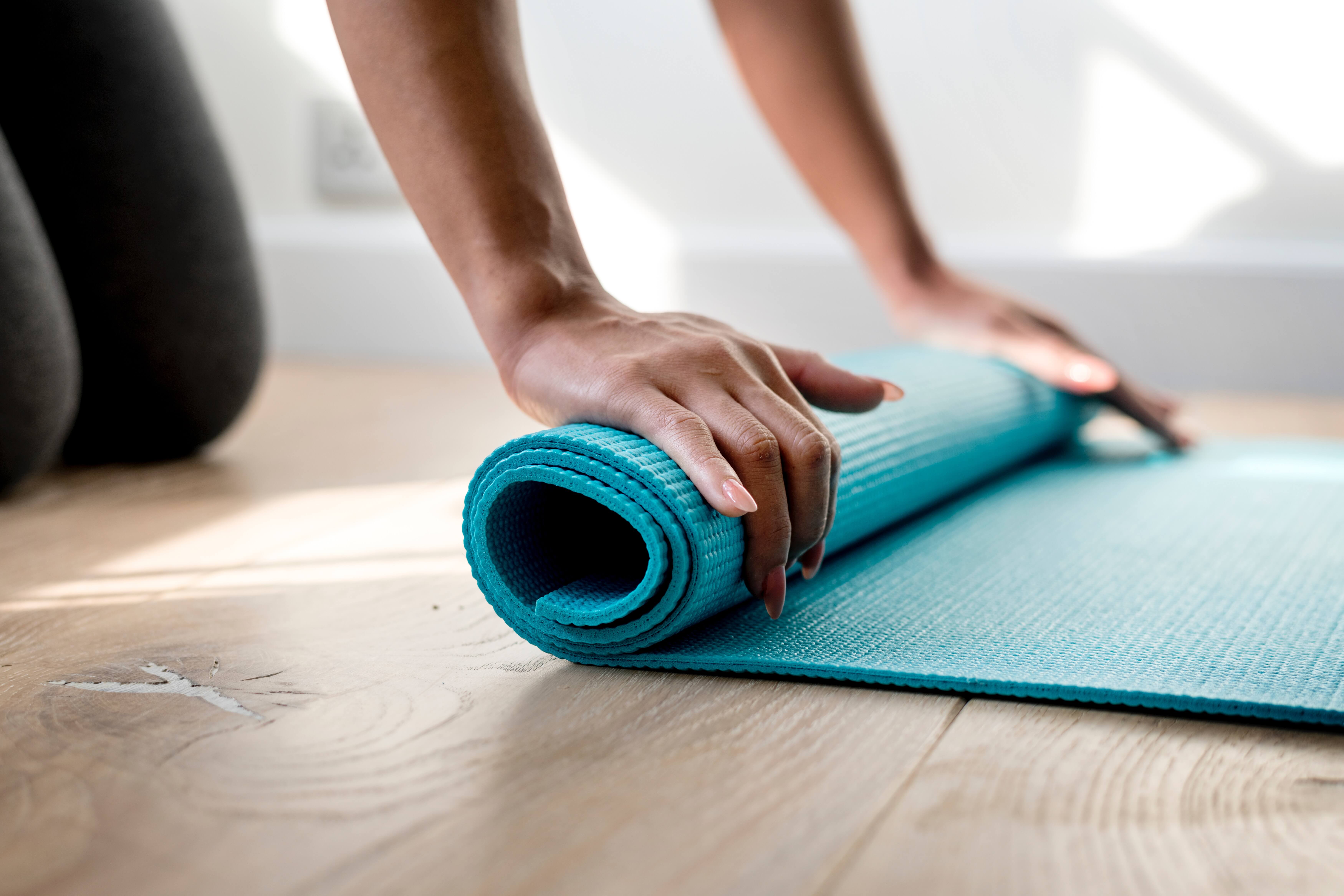 Proper nutrition along side moderate exercise is recommended during pregnancy - a woman folding yoga rug on the flor.