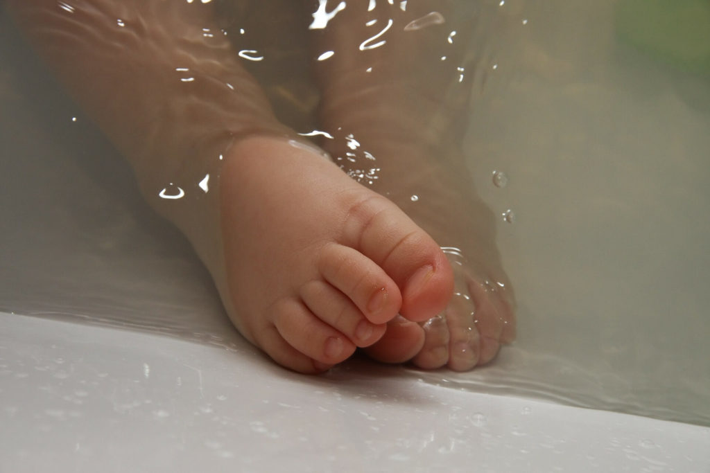caring for a newborn-newborn's feet in a tab full of water