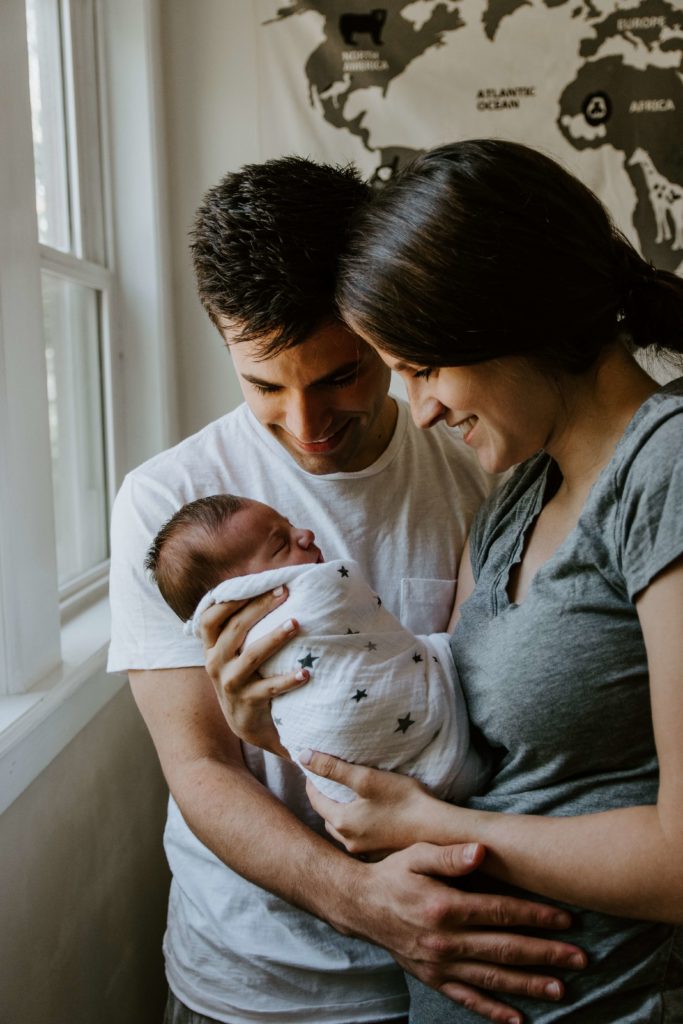 caring for a newborn-newborn in woman's arms next to a man.